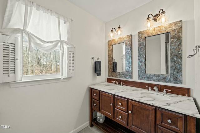 full bath featuring double vanity, baseboards, and a sink