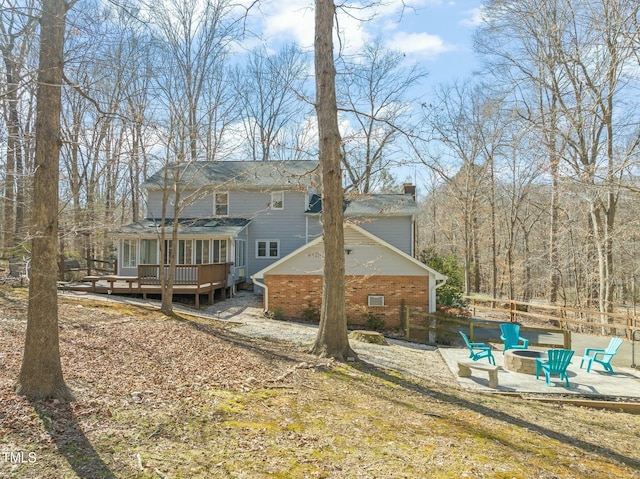 rear view of property with an outdoor fire pit, a patio, a chimney, a deck, and brick siding