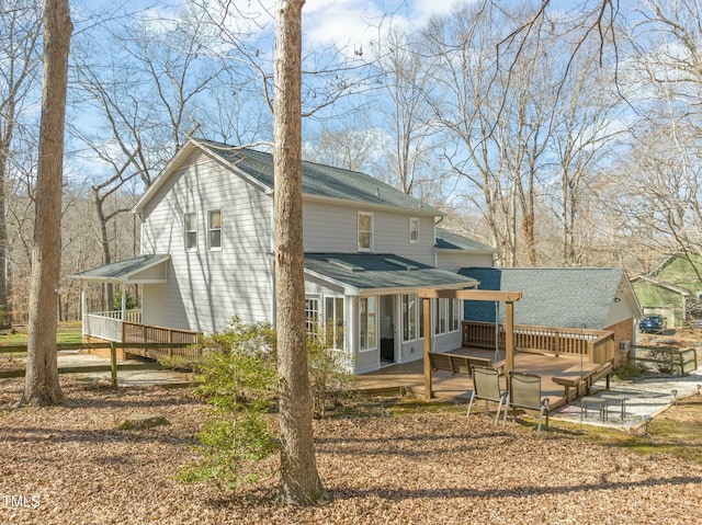 back of house with roof with shingles and a wooden deck