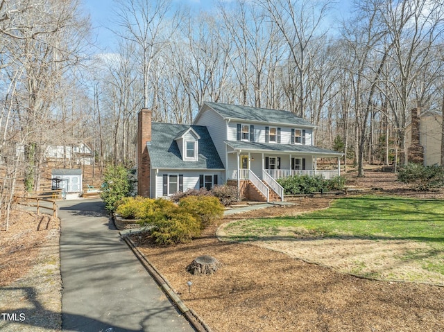 view of front of home featuring a porch, a front yard, and a chimney