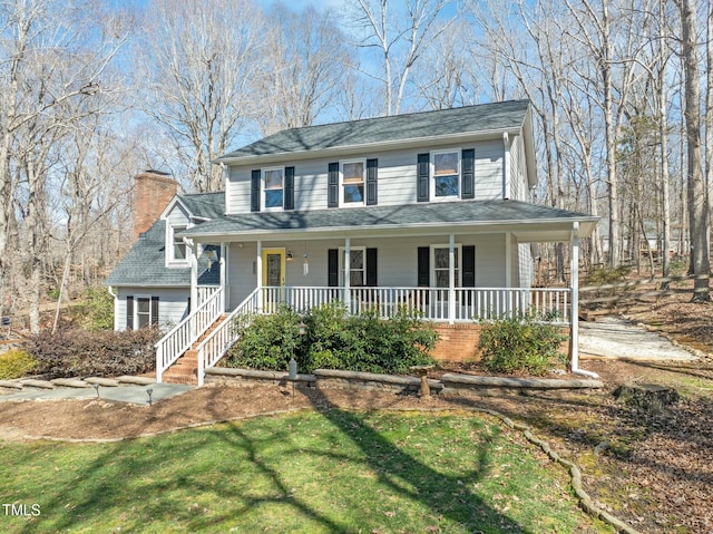 view of front facade featuring covered porch, a shingled roof, a chimney, and a front yard