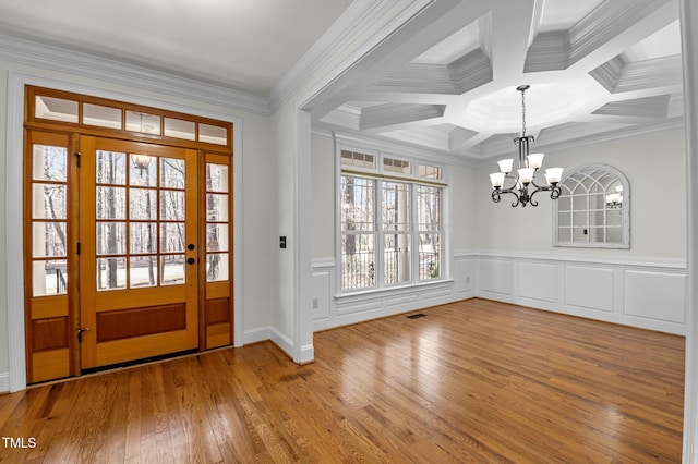 foyer featuring hardwood / wood-style floors, visible vents, coffered ceiling, an inviting chandelier, and ornamental molding