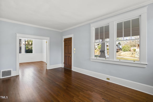 empty room featuring dark wood-style flooring, visible vents, crown molding, and baseboards