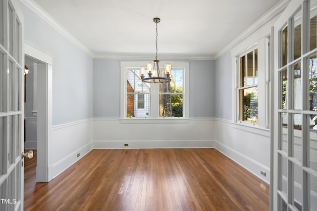 spare room featuring an inviting chandelier, baseboards, ornamental molding, and wood finished floors