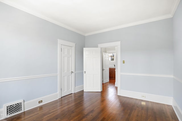 empty room featuring baseboards, crown molding, visible vents, and wood finished floors