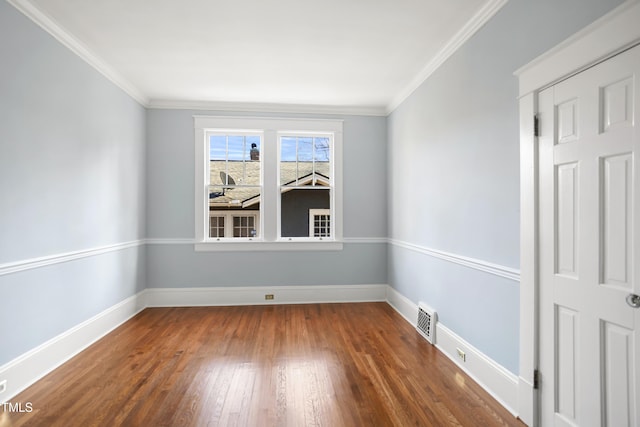 spare room featuring hardwood / wood-style floors, baseboards, visible vents, and crown molding