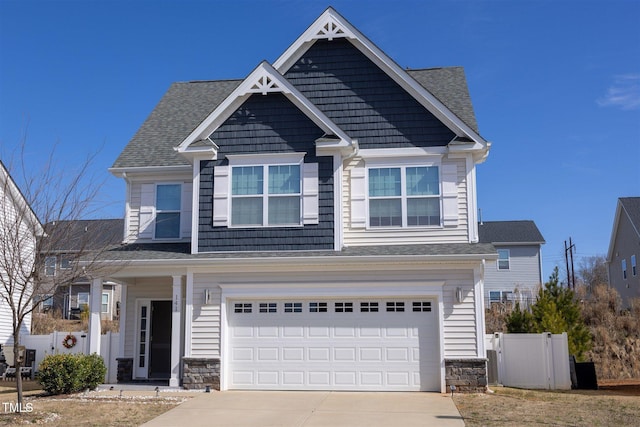 craftsman-style home featuring a shingled roof, fence, a garage, stone siding, and driveway