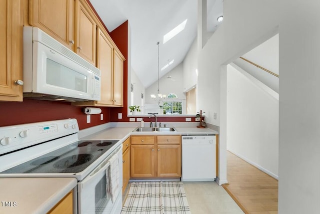 kitchen with white appliances, a skylight, light countertops, a chandelier, and a sink