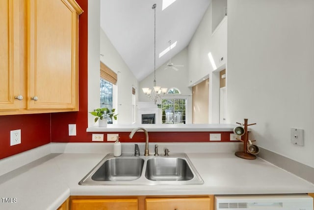 kitchen with vaulted ceiling with skylight, a sink, light countertops, dishwasher, and an inviting chandelier