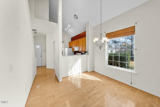 kitchen featuring high vaulted ceiling, light wood-type flooring, white appliances, and an inviting chandelier