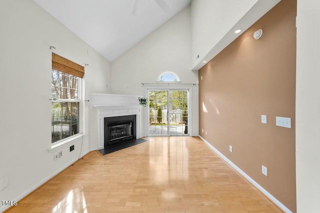 unfurnished living room featuring high vaulted ceiling, a fireplace, light wood-style flooring, and baseboards