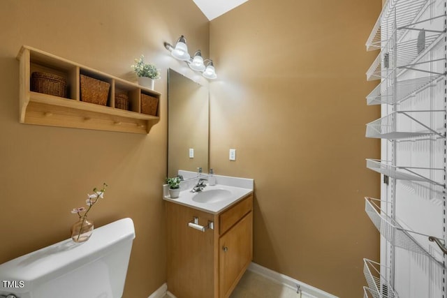 half bathroom featuring toilet, baseboards, and vanity