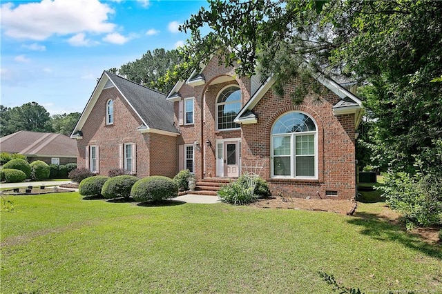 traditional home with a shingled roof, a front lawn, and brick siding