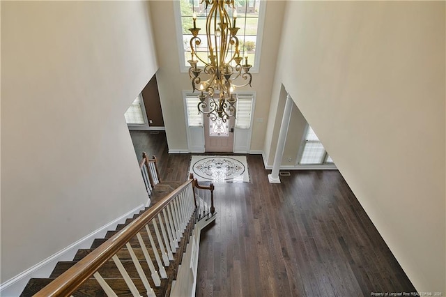 entrance foyer with a chandelier, wood finished floors, a towering ceiling, and baseboards