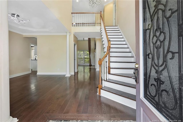 entryway with decorative columns, baseboards, crown molding, and wood finished floors