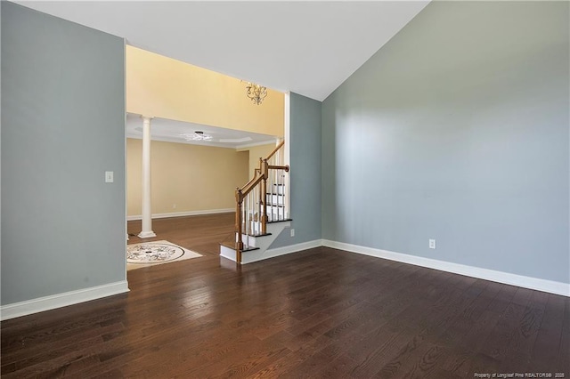 unfurnished room with wood finished floors, baseboards, ornate columns, and stairs