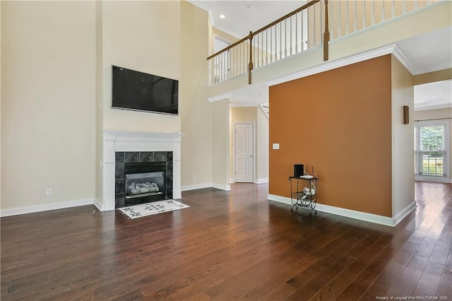 unfurnished living room with a fireplace, wood finished floors, a towering ceiling, and baseboards