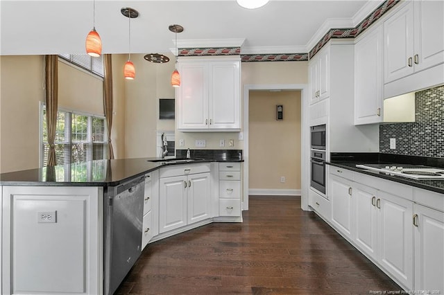 kitchen with dark wood finished floors, stainless steel appliances, dark countertops, a sink, and a peninsula