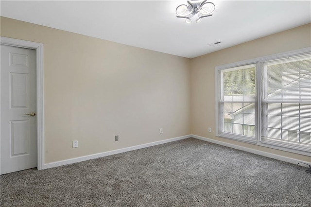 carpeted spare room featuring visible vents and baseboards