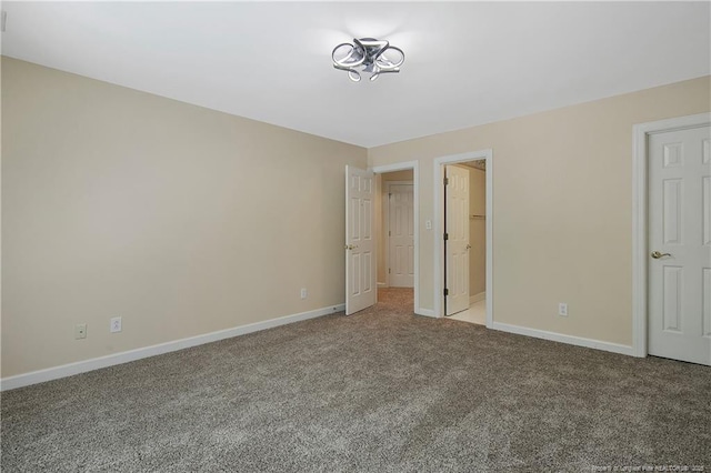 unfurnished bedroom with light carpet, a spacious closet, and baseboards