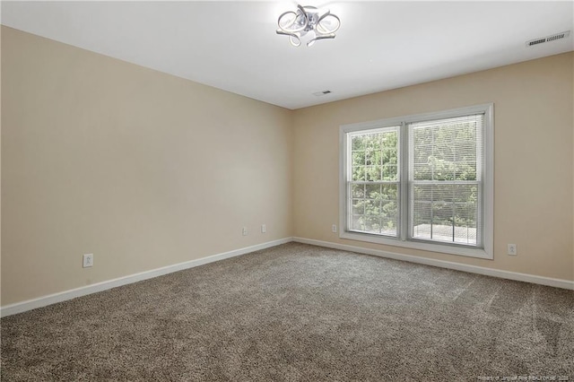 carpeted spare room featuring visible vents and baseboards