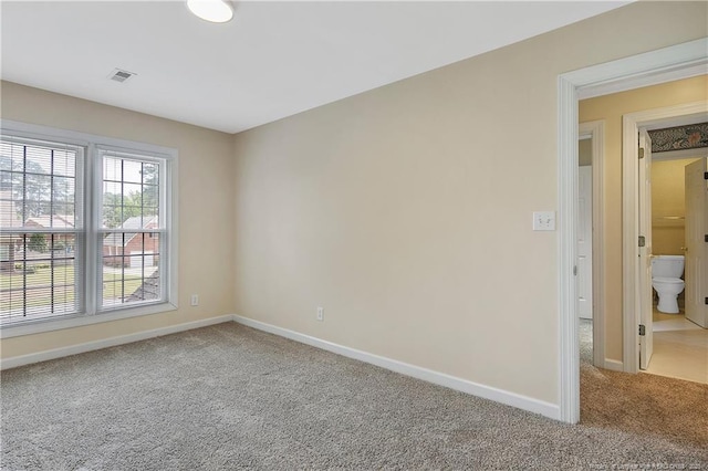 unfurnished room with carpet flooring, visible vents, and baseboards