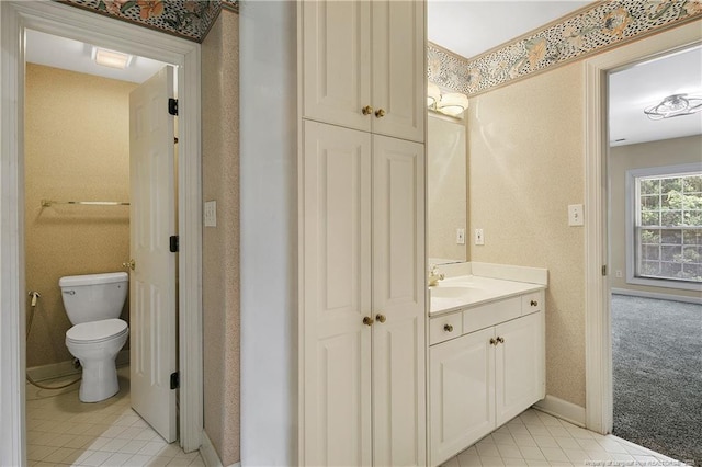 bathroom with toilet, tile patterned flooring, baseboards, and vanity