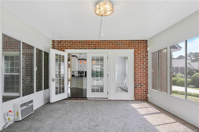 unfurnished sunroom featuring a wall mounted AC and plenty of natural light