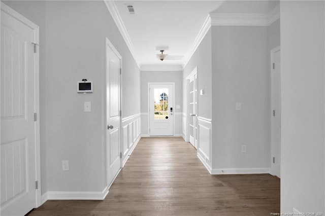 entryway with visible vents, crown molding, baseboards, and wood finished floors