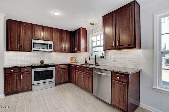 kitchen with a sink, dark stone countertops, backsplash, and stainless steel appliances