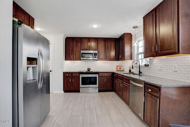 kitchen with stone counters, a sink, appliances with stainless steel finishes, pendant lighting, and tasteful backsplash