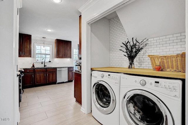 washroom featuring a sink, crown molding, laundry area, and washer and clothes dryer