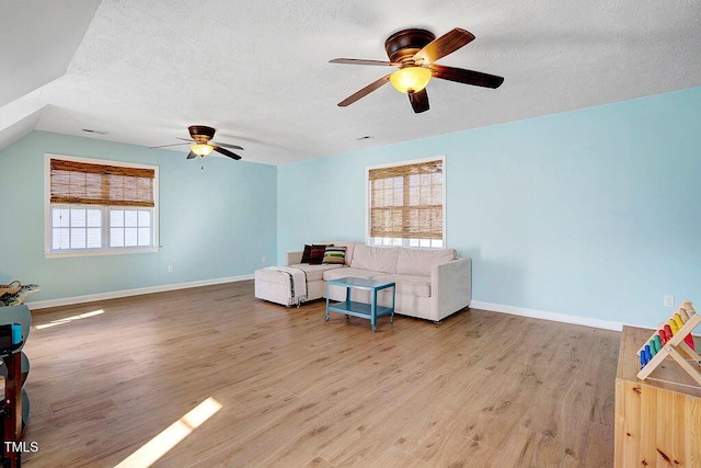 living area with light wood-type flooring, baseboards, a textured ceiling, and ceiling fan