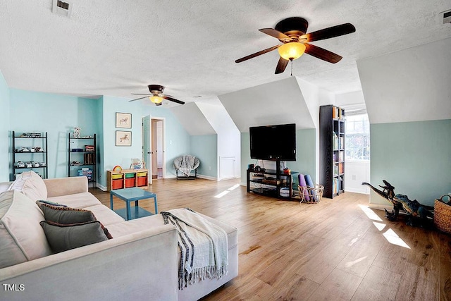 living area with vaulted ceiling, visible vents, a ceiling fan, and wood finished floors