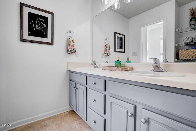 full bathroom featuring tile patterned flooring, double vanity, baseboards, and a sink