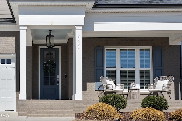 property entrance with roof with shingles, a porch, and brick siding