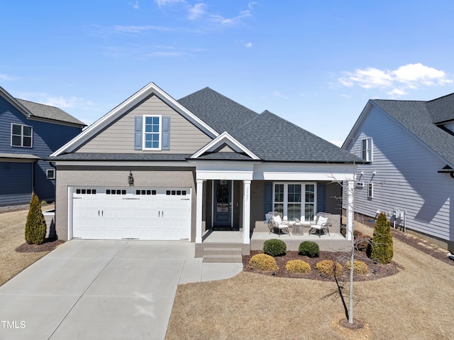 view of front facade featuring roof with shingles, brick siding, concrete driveway, an attached garage, and a patio area