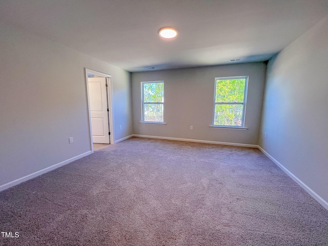 unfurnished room featuring carpet flooring, visible vents, and baseboards