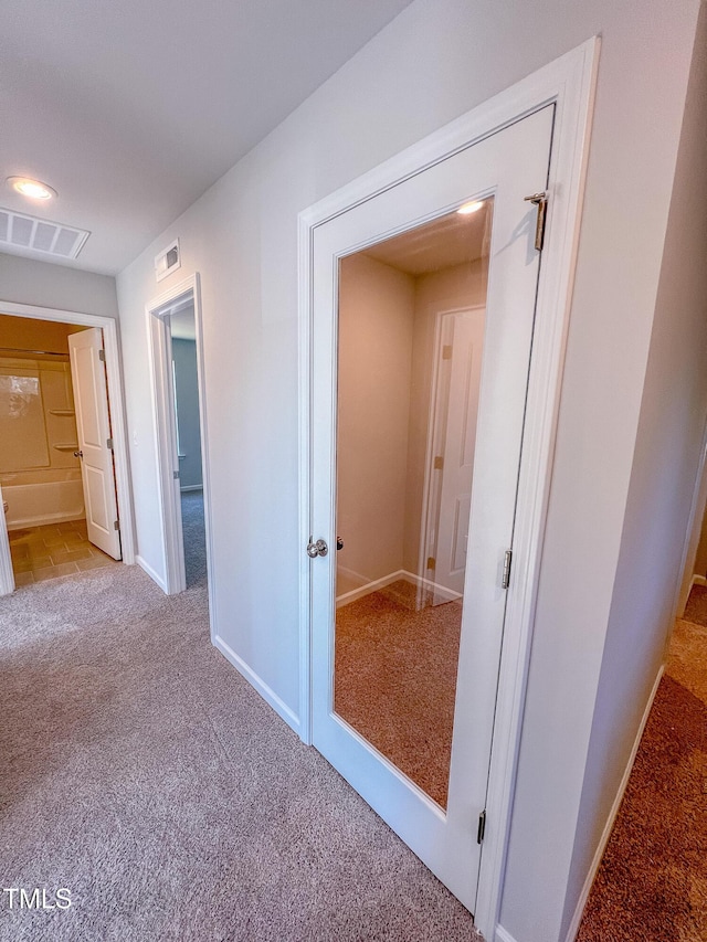 corridor featuring baseboards, visible vents, and carpet flooring