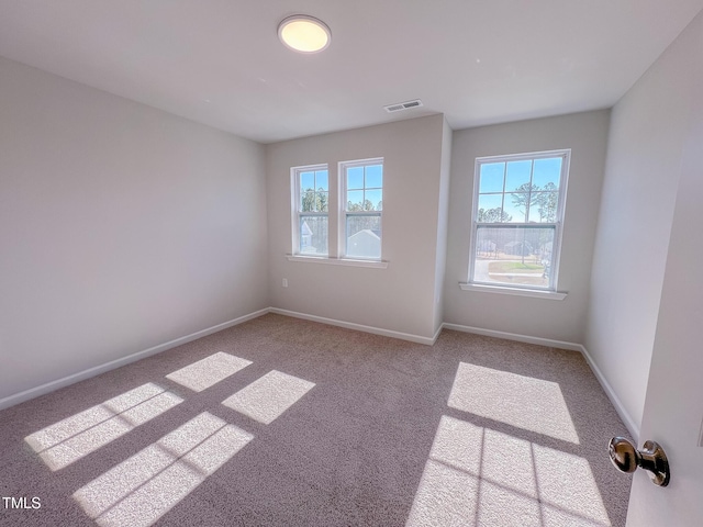 carpeted spare room featuring baseboards and visible vents