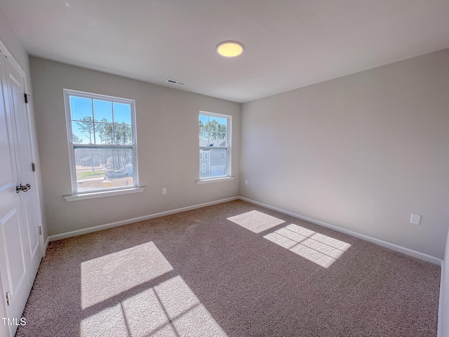 carpeted spare room featuring visible vents and baseboards