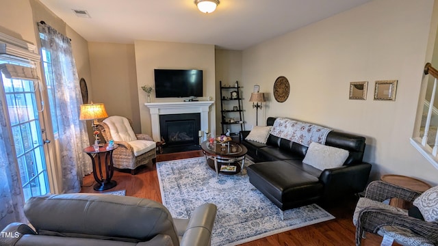 living area with a glass covered fireplace, wood finished floors, and visible vents