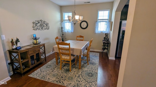 dining space with arched walkways, visible vents, dark wood finished floors, and baseboards