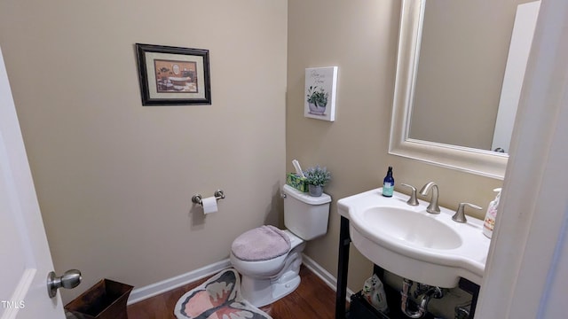 bathroom with baseboards, a sink, toilet, and wood finished floors