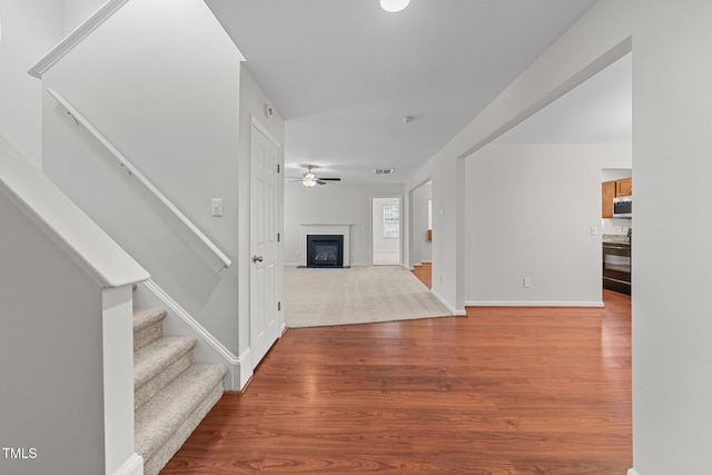 entrance foyer featuring ceiling fan, a fireplace with flush hearth, wood finished floors, visible vents, and stairs