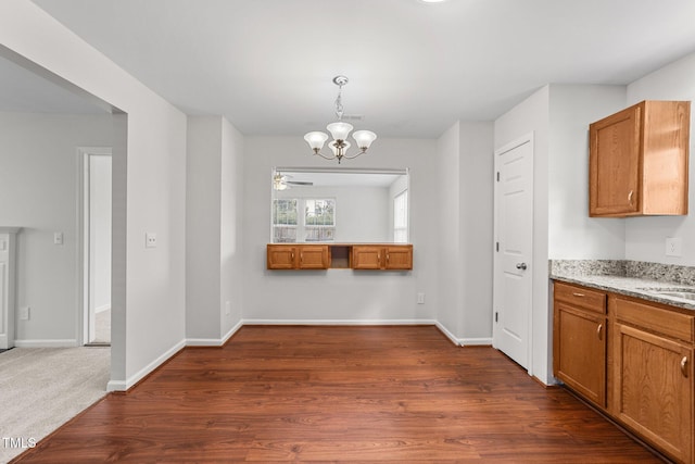 unfurnished dining area with a chandelier, dark wood-type flooring, a sink, and baseboards