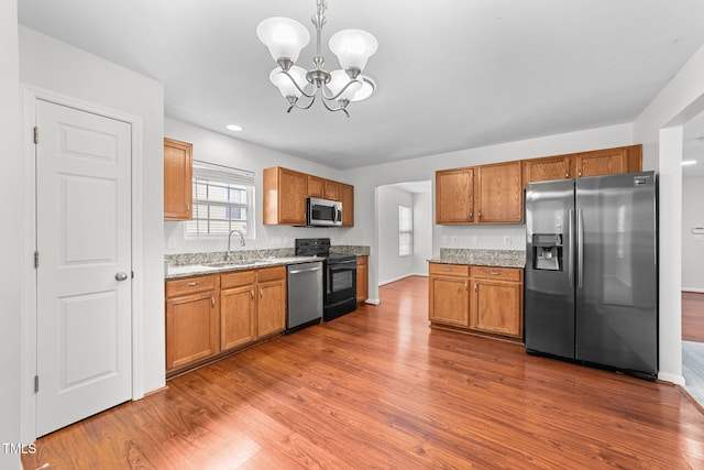 kitchen with brown cabinetry, appliances with stainless steel finishes, dark wood-type flooring, and a sink