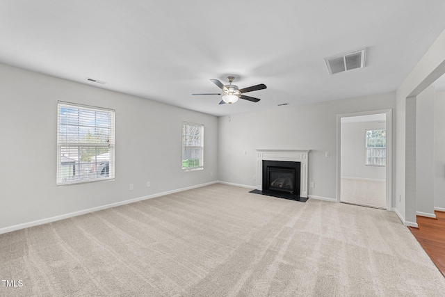 unfurnished living room with a fireplace with flush hearth, visible vents, and baseboards