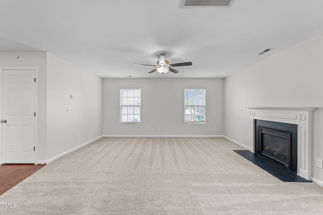 unfurnished living room with carpet, visible vents, baseboards, and a fireplace with flush hearth