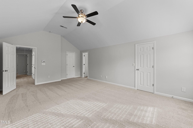 interior space featuring lofted ceiling, baseboards, attic access, and light colored carpet